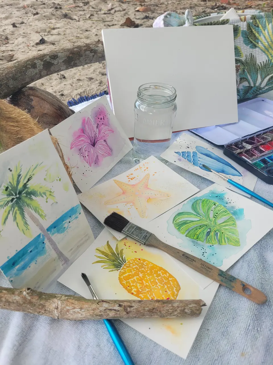 Pinceaux, bois flotté et cartes peintes à l’aquarelle sur la plage