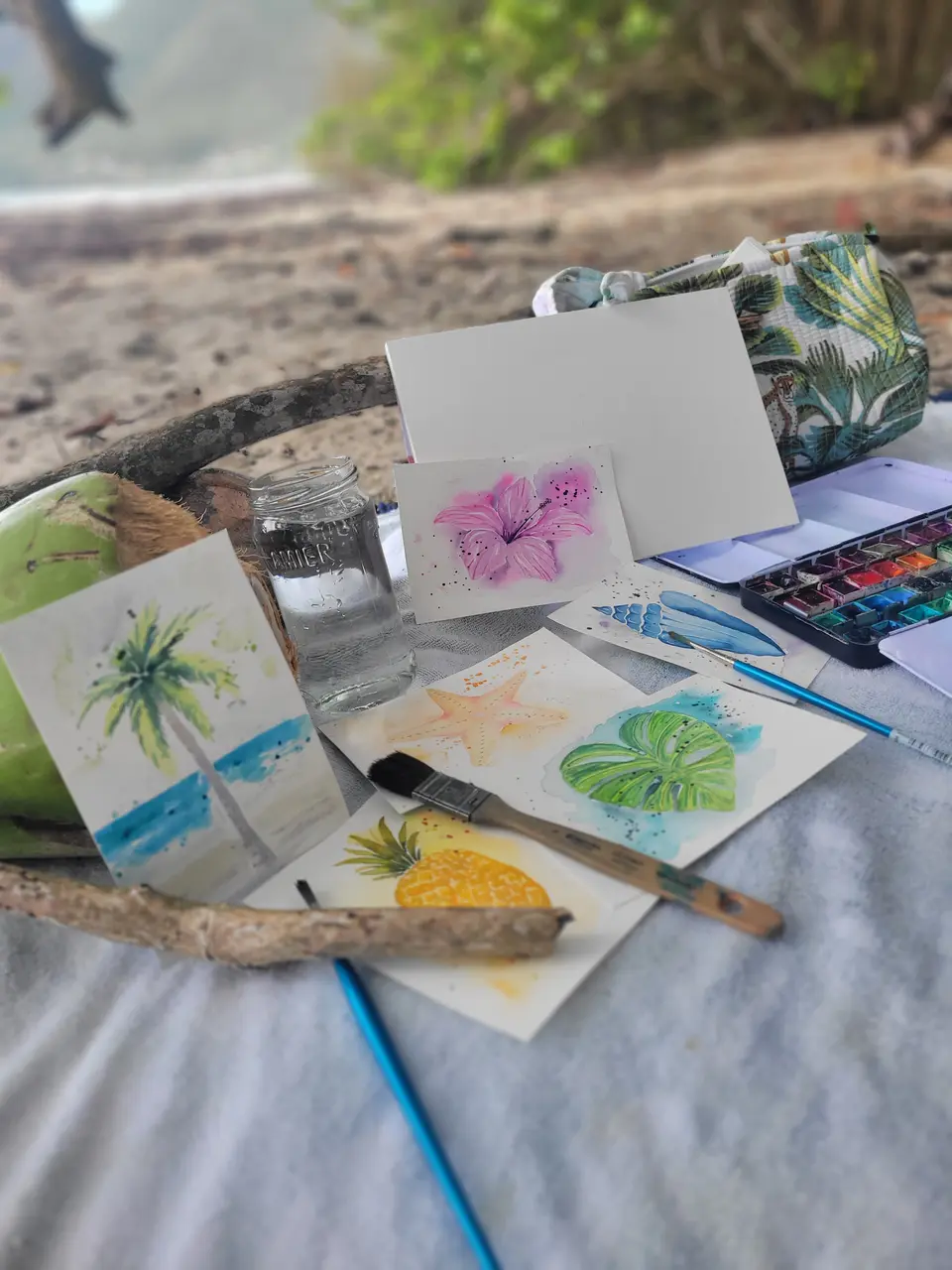 Bocal d’eau, noix de coco et cartes à l’aquarelle à l’ombre des raisiniers